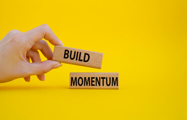 Build momentum symbol. Wooden blocks with words Build momentum. Beautiful yellow background. Businessman hand. Business and Build momentum concept. Copy space.