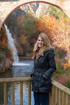 Uşak, Turkey - November 2016: Young girl posing against out focus Clandras Bridge. Historical bridge from the Phrygian period in the district of Karahallı in Usak province.