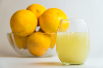 yellow grapefruit in glass fruit bowl on yellow table, glass of milk