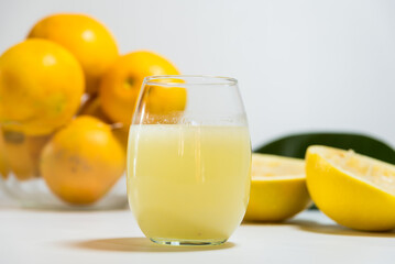Fototapeta na wymiar peels of yellow grapefruit squeezed next to a glass of its juice, leaves on the table
