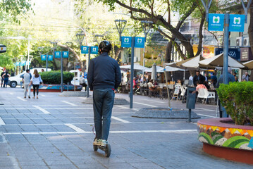 person riding an electric scooter through the central streets of Mendoza Argentina
