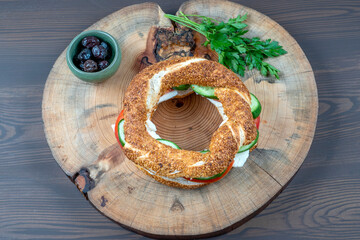 Delicious Traditional Turkish breakfast with Turkish bagel (simit ) include tomatoes, cheese, olives served on a wooden plate.