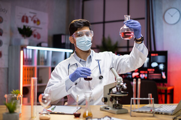 Young scientist arab man lab technical service holding flask with lab glassware and test tubes in chemical laboratory background, science laboratory research and development medicines.