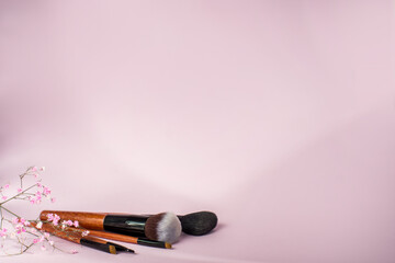 eye makeup brushes lie near a palette of eyeshadows on a pink background