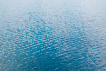Abstraction of the surface of blue water reflected by sunlight as a background.Top view of the sea water. The concept of relaxing on the beach, vacations.The texture of the waves.