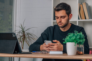 young man at home with mobile phone and laptop