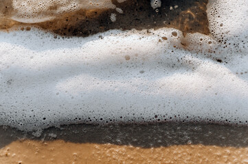 Background, texture from the beach of white foam from the sea, ocean on the sand.
