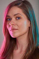 young woman face beauty portrait with multicolored light. futuristic look girl natural skin and long hair.