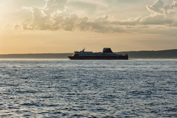 Obraz premium Car ferry leaving the port of Marseille, France. Car ferry on sunset cloud background. Ferry sailing across the Mediterranean sea. Passenger ship on the ocean. 