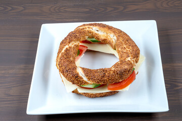 Turkish Bagel Simit Sandwich. Turkish bagel made at home with with cheese, tomato and cucumber on a...