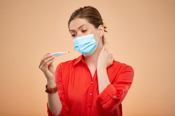 Sick woman with medical mask looking on digital thermometer, isolated female portrait. Girl in red shirt.