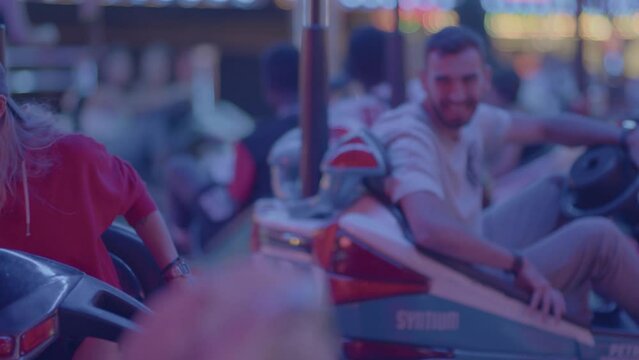 4k SlowMo - Young couple at the village fair, crashing cars. Boy flirting with her, they have a good time
