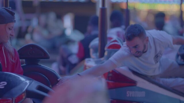 4k SlowMo - Young couple at the village fair, crashing cars. Boy flirting with her, they have a good time
