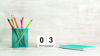 September 3 calendar. The concept of the date of the season. Pencils in a basket against the background of a notebook and the date of the month. Copy space calendar cube.