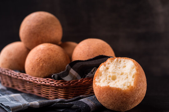 Round colombian traditional food named bu&ntilde;uelo in a basket on black wooden table 