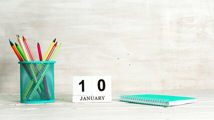 January 10 calendar. The concept of the date of the season. Pencils in a basket against the background of a notebook and the date of the month. Copy space calendar cube.