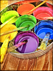 Multi-colored paints are in buckets on the wooden background. 