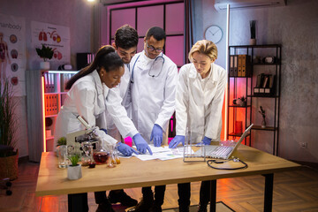 Modern electronics development facility. Diverse team of multiethnic scientists standing near table...
