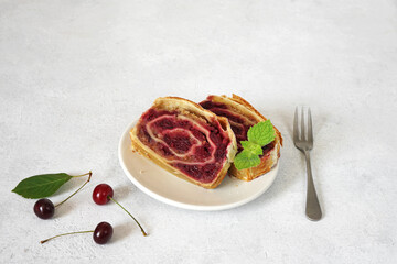 pieces of Cherry strudel with fresh mint on the plate on light bakground, copy space