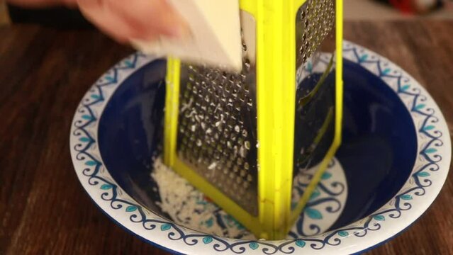 Chef grating cheese. Woman making recipe with cheese. Cheese grater.