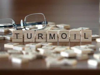 Fotobehang turmoil word or concept represented by wooden letter tiles on a wooden table with glasses and a book © lexiconimages
