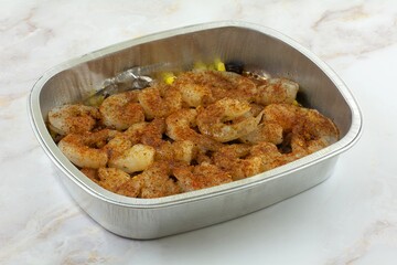 Raw shrimp with taco seasoning and corn and black bean vegetables in aluminum foil baking pan