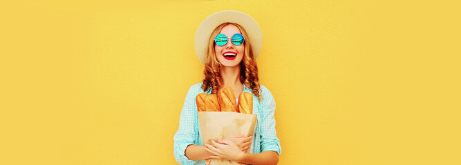 Portrait of happy smiling young woman holding grocery shopping paper bag with long white bread...