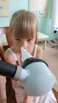 Treatment and warming of little girl's nose with the help of the KUF apparatus. Little girl is sitting in physiotherapy room for a procedure.