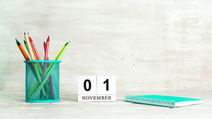 November 1 calendar. The concept of the date of the season. Pencils in a basket against the background of a notebook and the date of the month. Copy space calendar cube.