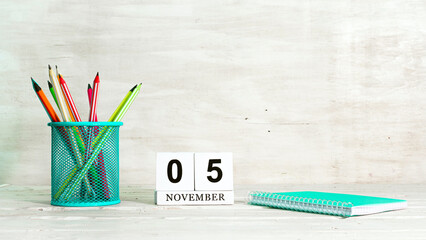 November 5 calendar. The concept of the date of the season. Pencils in a basket against the background of a notebook and the date of the month. Copy space calendar cube.