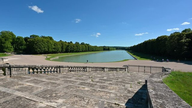Versailles, Paris, France, June 2022. Beautiful pan footage from the Grand Trianon towards the branch of the grand canal de Versailles, makes the observer understand the vastness of the palace park.