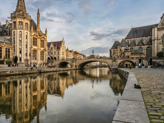 Historic medieval building and Arched stone bridge at night on Leie river in Ghent, Belgium