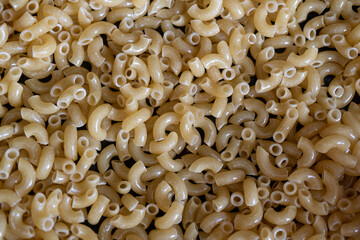 friendo pasta de coditos en sartén de teflón con palita de madera