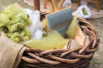 White and green wool, unkempt and rolag with a handcard in a basket, preparation for spinning,...