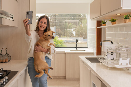 Woman taking a selfie while holding a dog in a new house