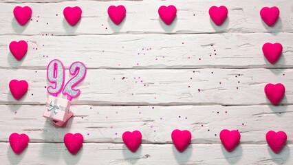 Happy birthday card for a girl in pink shades, top view, copy space. Beautiful congratulations with numbers and hearts, a place for your text. happy birthday candle number 92