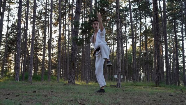 Man training karate in the forest one male athlete karateka caucasian practitioner doing kata in nature in the woods in day real people