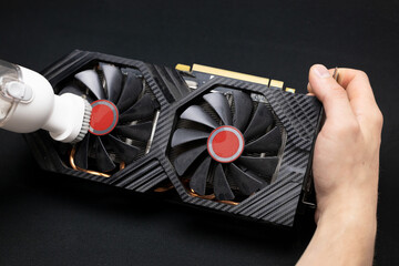 Computer master cleans the video card from dust with a vacuum cleaner