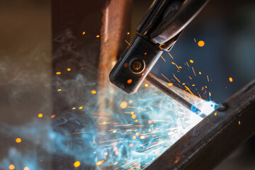 Welding close-up, a lot of sparks and smoke from electronic welding, industrial area