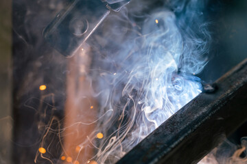Fototapeta na wymiar Welding close-up, a lot of sparks and smoke from electronic welding, industrial area
