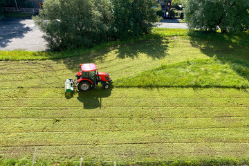 Tractor mows the grass in the yard of the house