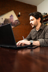 Obraz na płótnie Canvas hombre con barba trabajando con computadora laptop en su casa, proyecto de diseño asistido