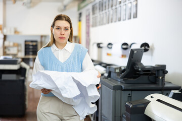 Portrait of sad woman printing office worker holding crumpled piece of paper.