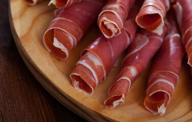 Spanish tasty meal rolls of prosciutto di parma at wooden desk, close up