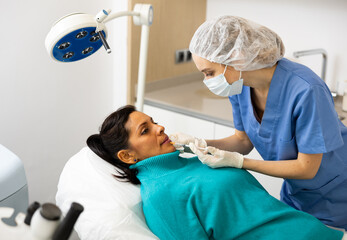 Portrait of young woman receiving injections for face skin rejuvenation treatments at beautician office