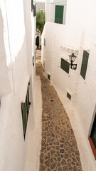 between streets of white facades in the fishing village, Menorca. - 520912178
