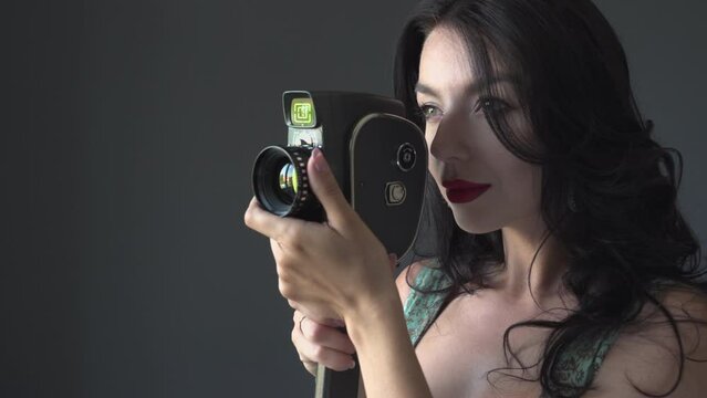 Young woman filmmaker who shoots on a 8mm film retro video camera. Retro movie concept