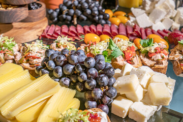 Delicious assortment of cheese plate with grapes and hams