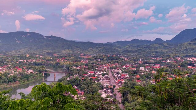 Time lapse day to night view of world heritage city of luang prabang with mountain on background.