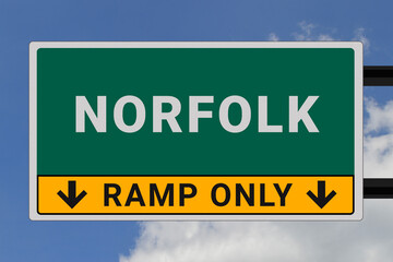 Norfolk logo. Norfolk lettering on a road sign. Signpost at entrance to Norfolk, USA. Green pointer in American style. Road sign in the United States of America. Sky in background